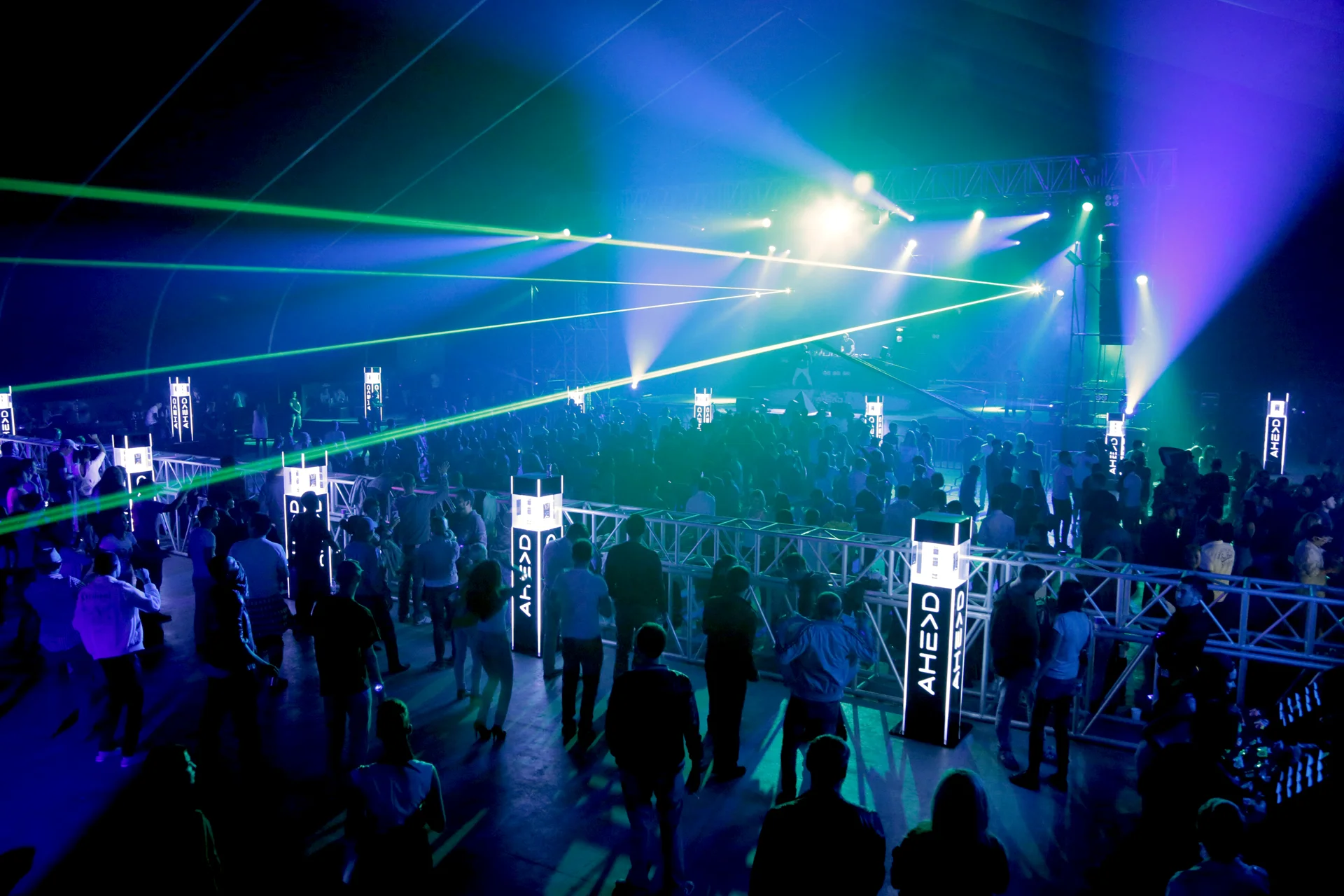 Зелёные лазерные лучи над танцполом в тентовой арене, фермовые башни по краям сцены